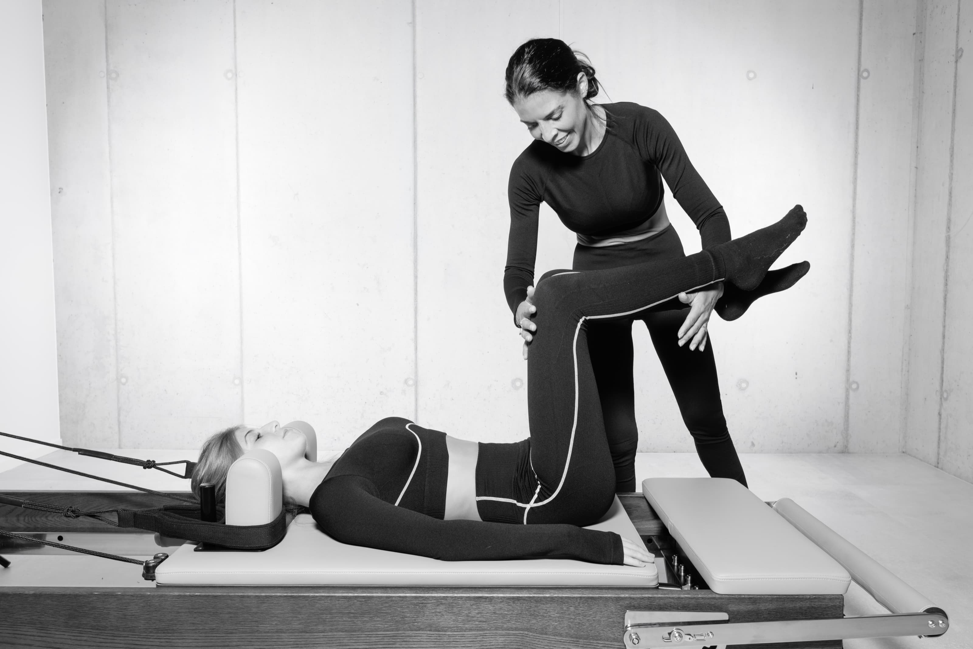 Lili guide une élève allongée sur le Reformer, une main sous le genou